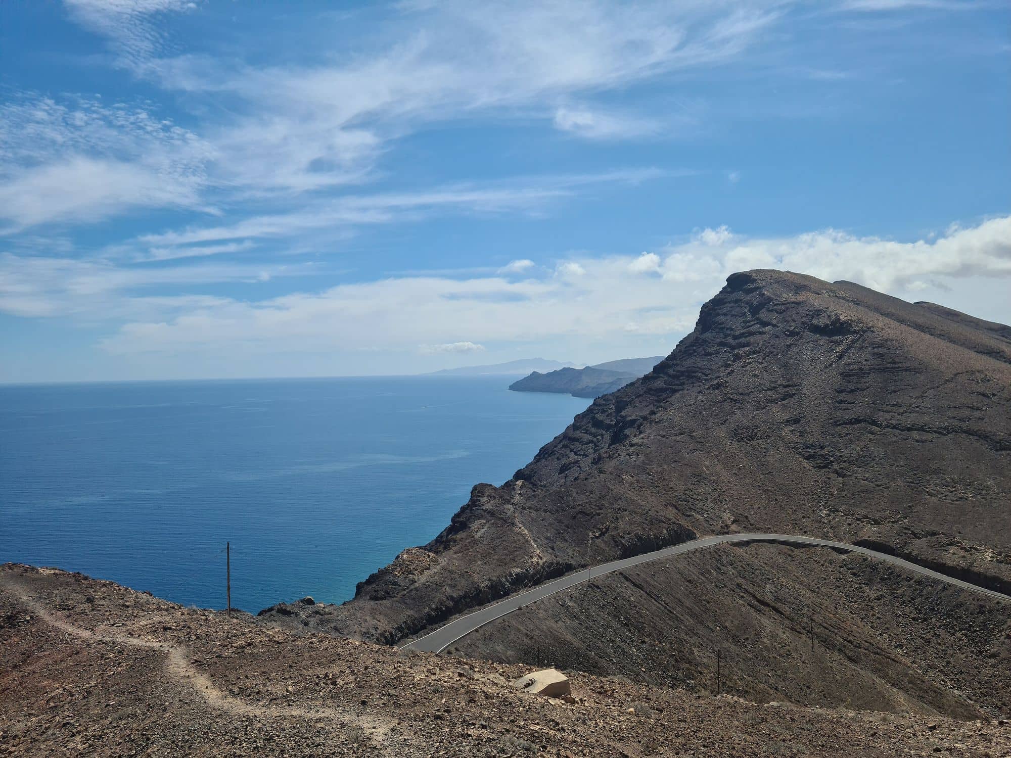 La strada che sale al faro della Entallada sopra la scogliera e l'oceano