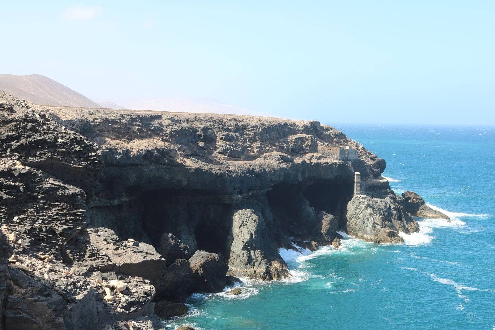 Il faro della Entallada in pietra scura sulla scogliera, nell'est di Fuerteventura