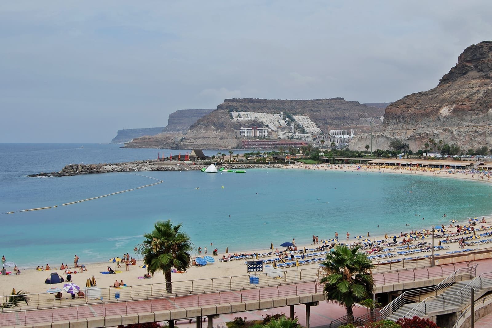 La baia di Amadores dall'alto: la spiaggia di sabbia chiara e l'acqua calma chiusa dalle dighe