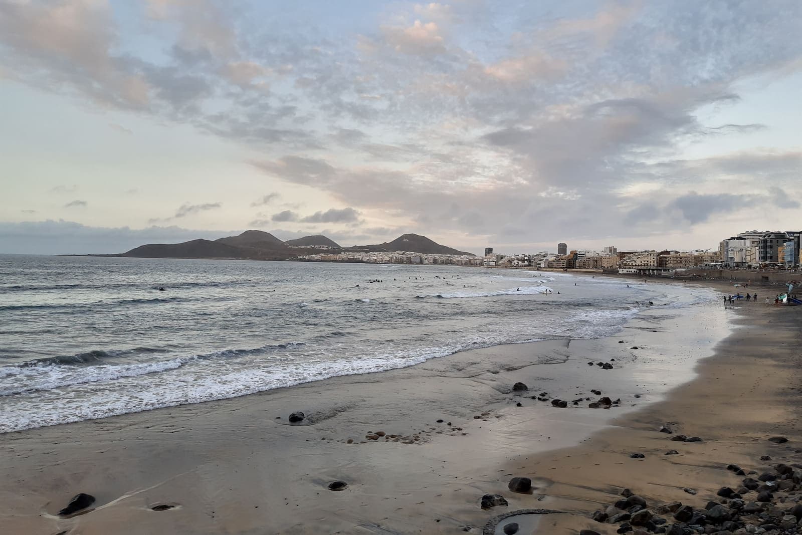La spiaggia di Las Canteras al tramonto, con le onde sulla riva e la città di Las Palmas sullo sfondo