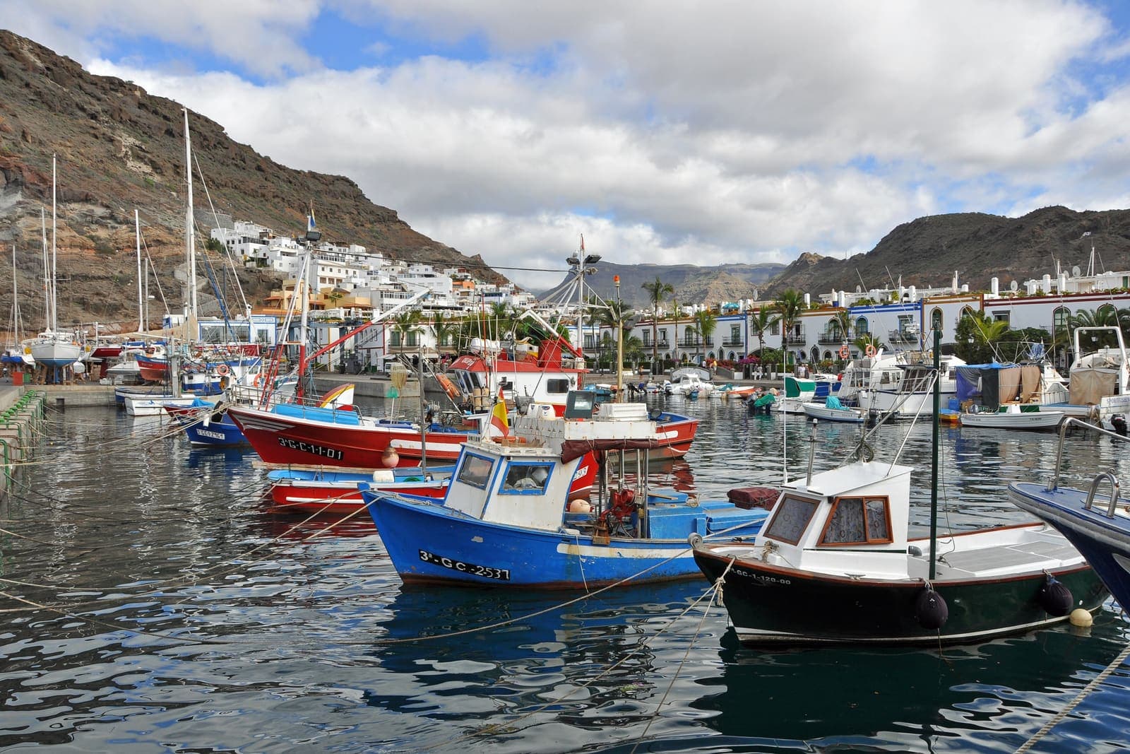 Le barche colorate nel porto di Puerto de Mogán, con le case bianche e le montagne alle spalle