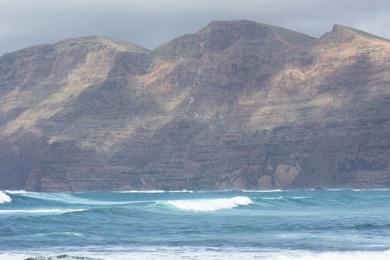 La scogliera del Risco de Famara sopra il mare mosso, vista da Caleta de Famara