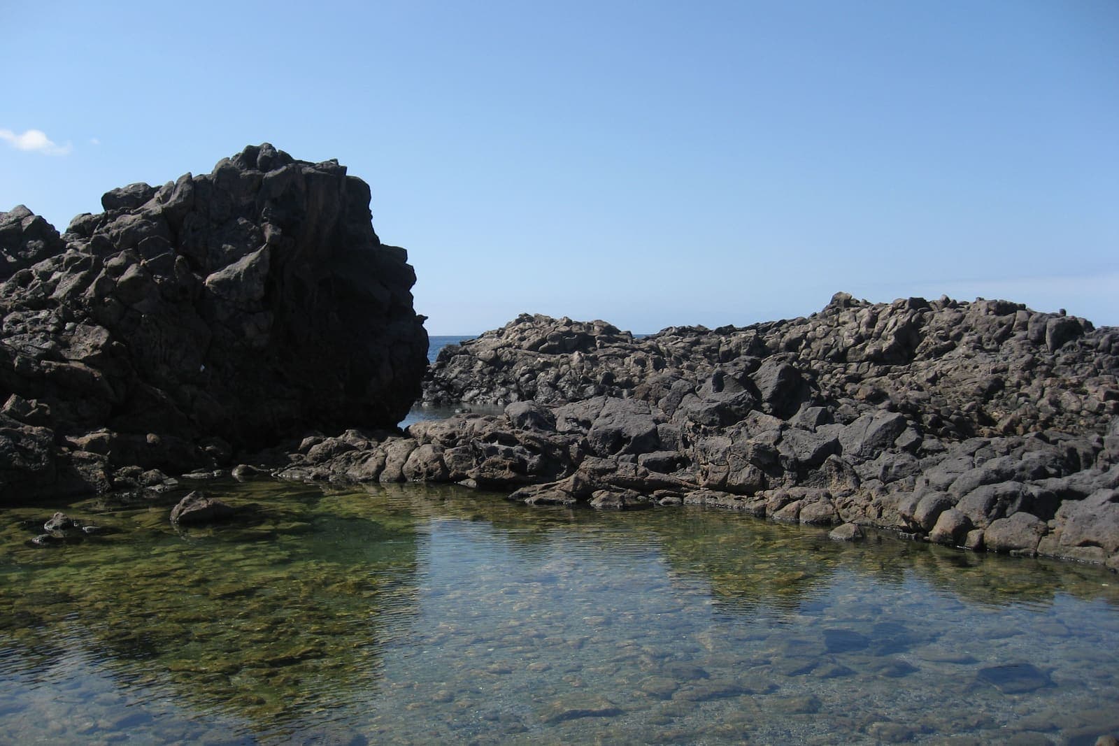 Rocce di lava scura e una pozza d'acqua limpida sulla costa del Malpaís de Rasca