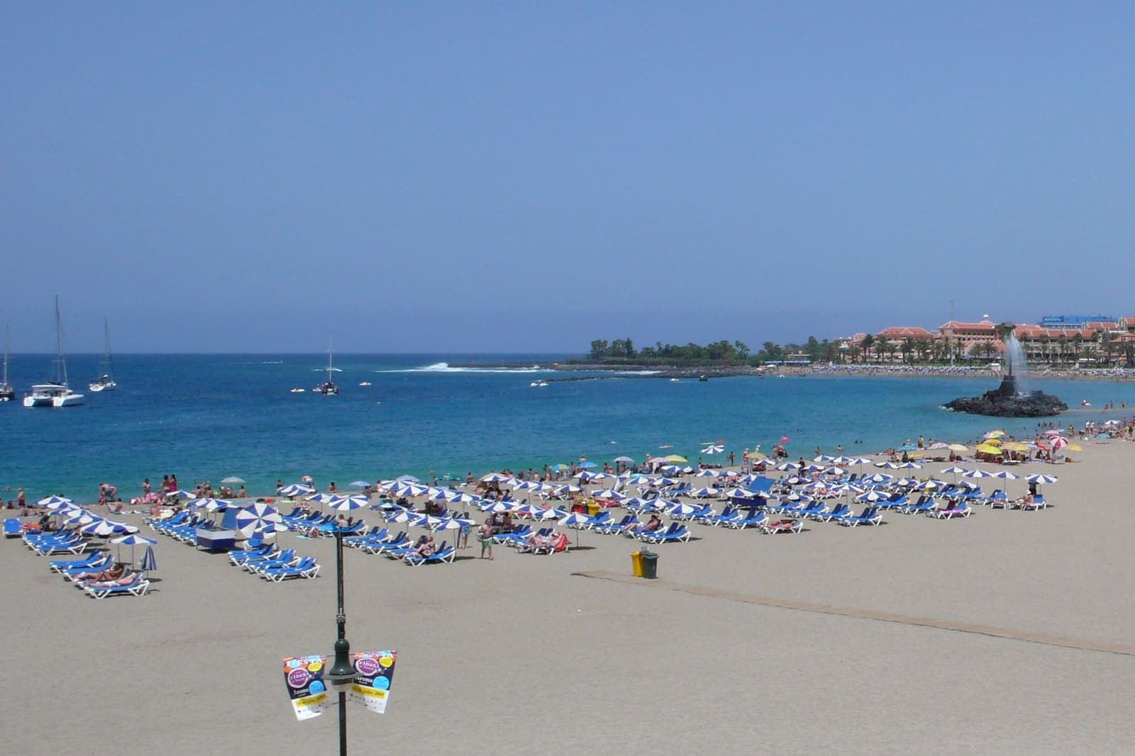 Playa de las Vistas a Los Cristianos: la spiaggia chiara con gli ombrelloni e l'acqua calma dietro il frangiflutti