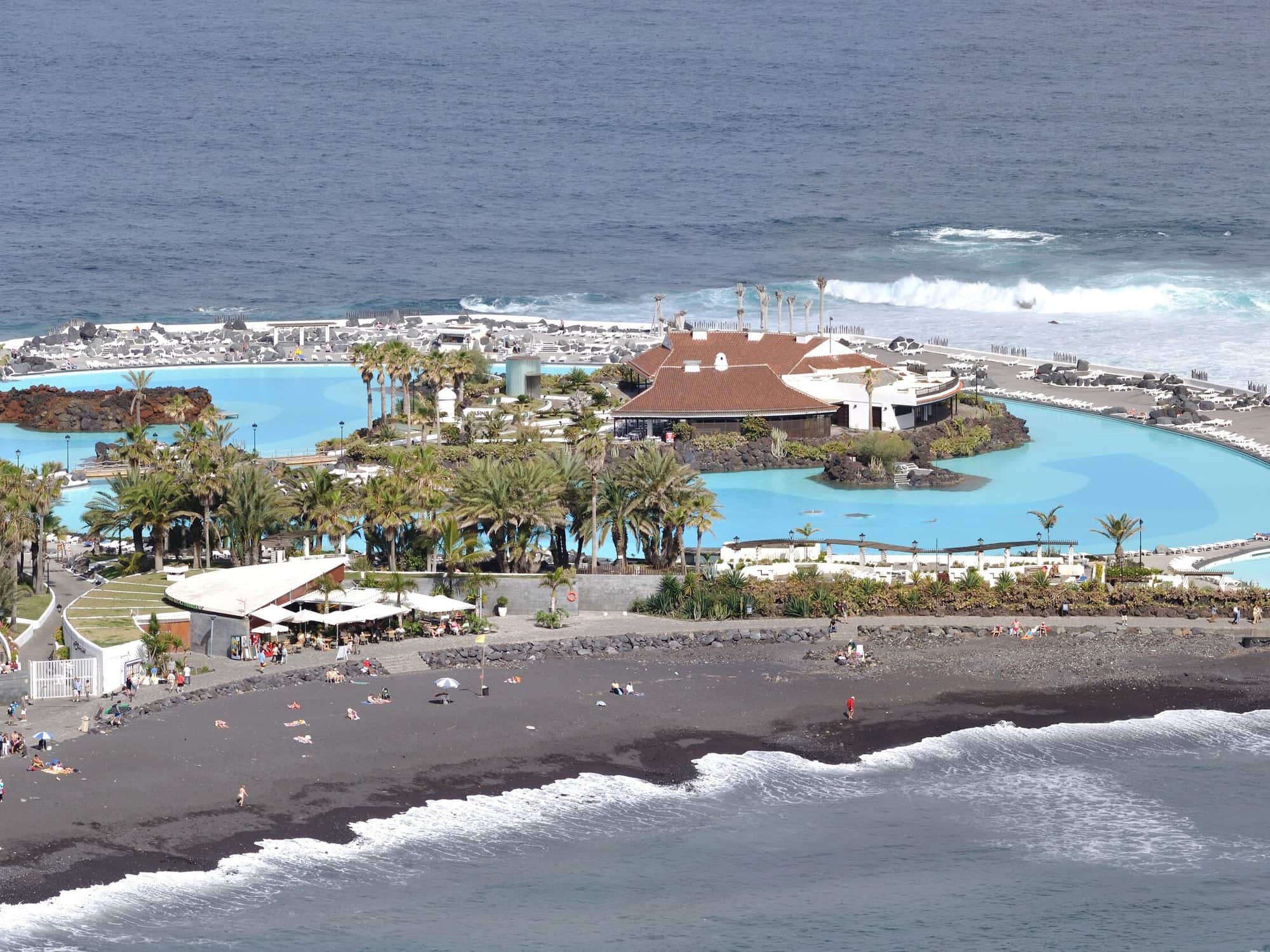Il Lago Martiánez a Puerto de la Cruz dall'alto: le piscine d'acqua salata fra le palme, la spiaggia nera e l'oceano