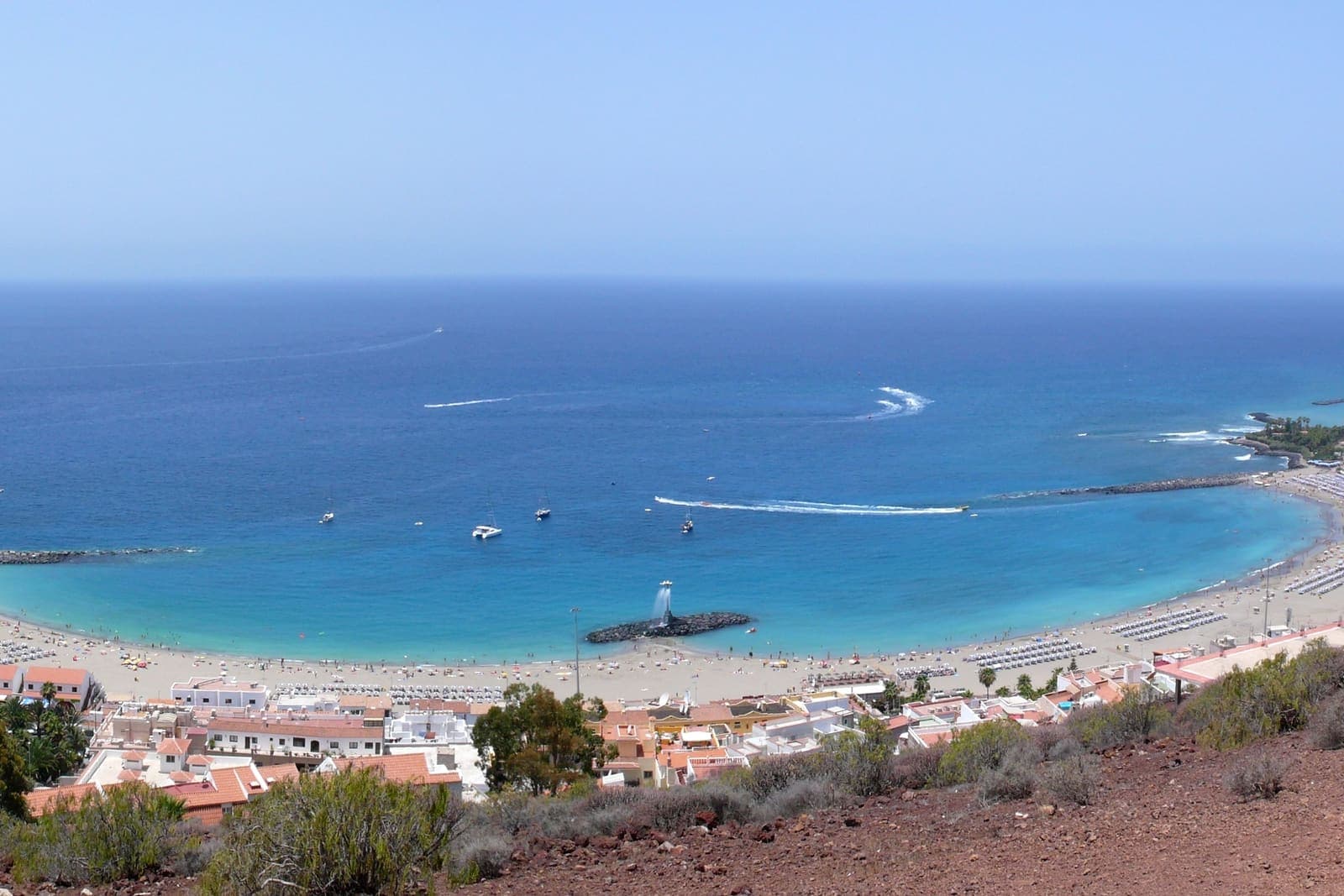 La baia di Playa de las Vistas a Los Cristianos vista dall'alto: l'acqua turchese e calma chiusa dai frangiflutti e la lunga spiaggia chiara